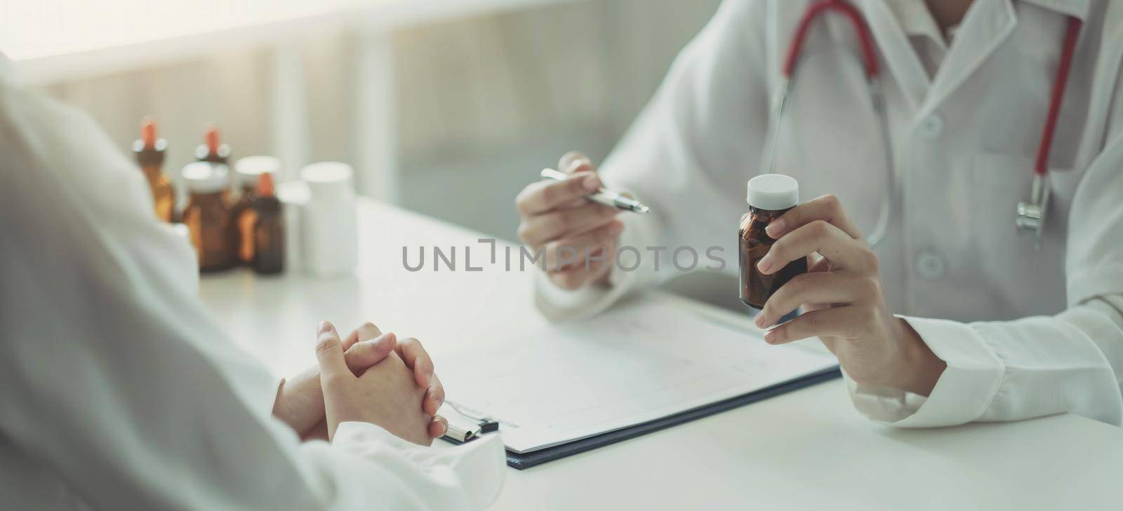 Confident man and woman holding pill bottle while talking to patient and reviewing medicine at office..