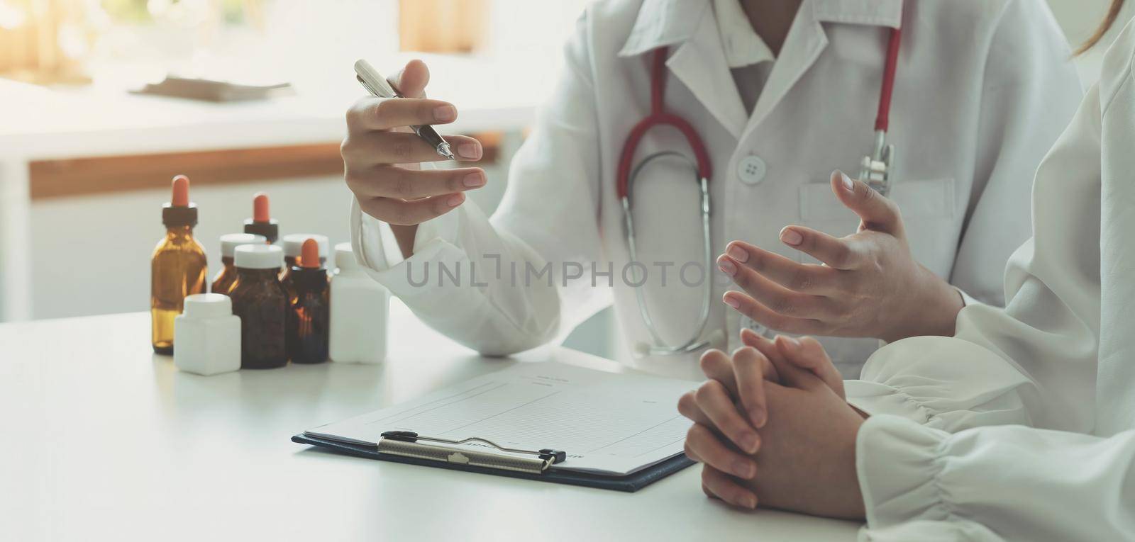 Doctor and patient discussing something while sitting at the table . Medicine and health care concept. Doctor and patient by wichayada