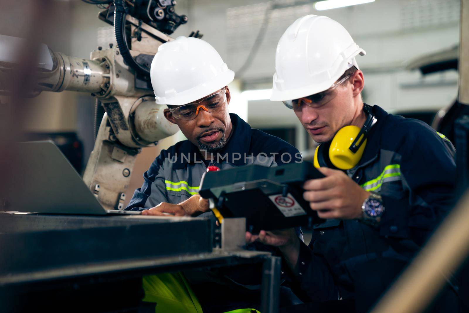 Factory workers working with adept robotic arm in a workshop . Industry robot programming software for automated manufacturing technology .