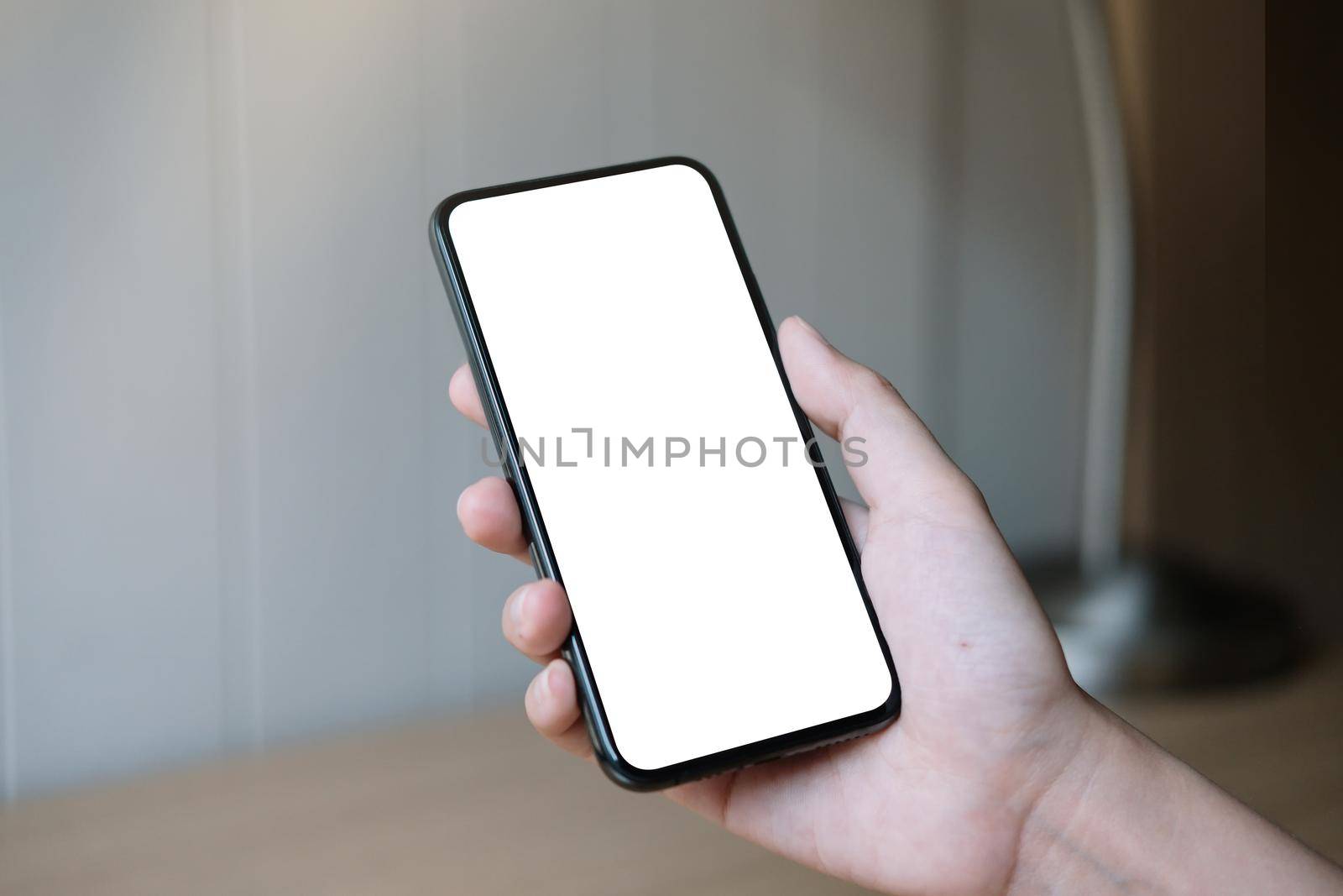 Woman hand holding smartphone with blank white screen.