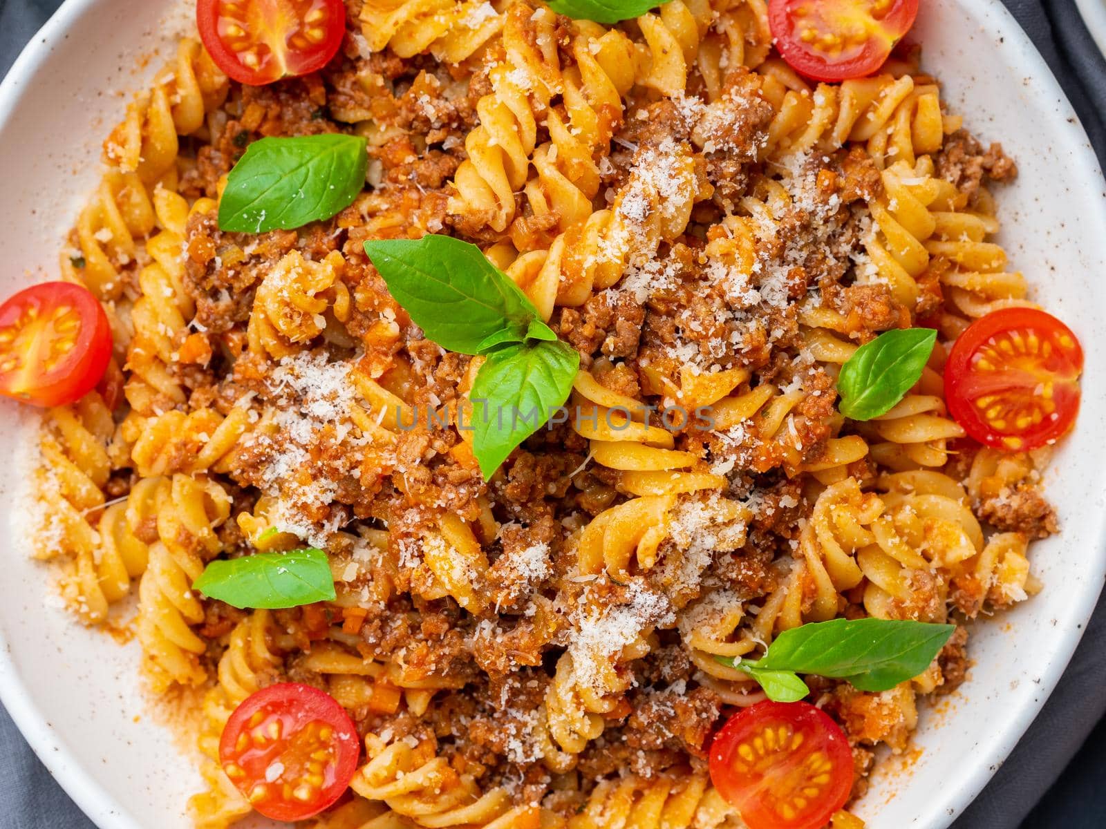 Bolognese pasta. Fusilli with tomato sauce, ground minced beef, basil leaves. Traditional italian cuisine. Top view, close up.
