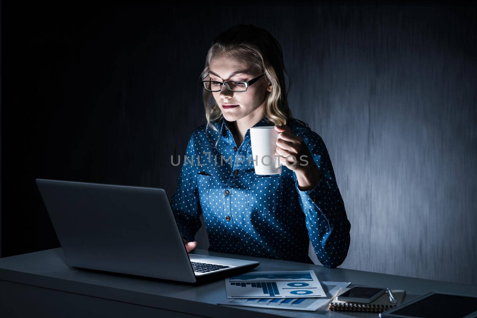 Young woman sitting in her room or office at late night. Mixed media