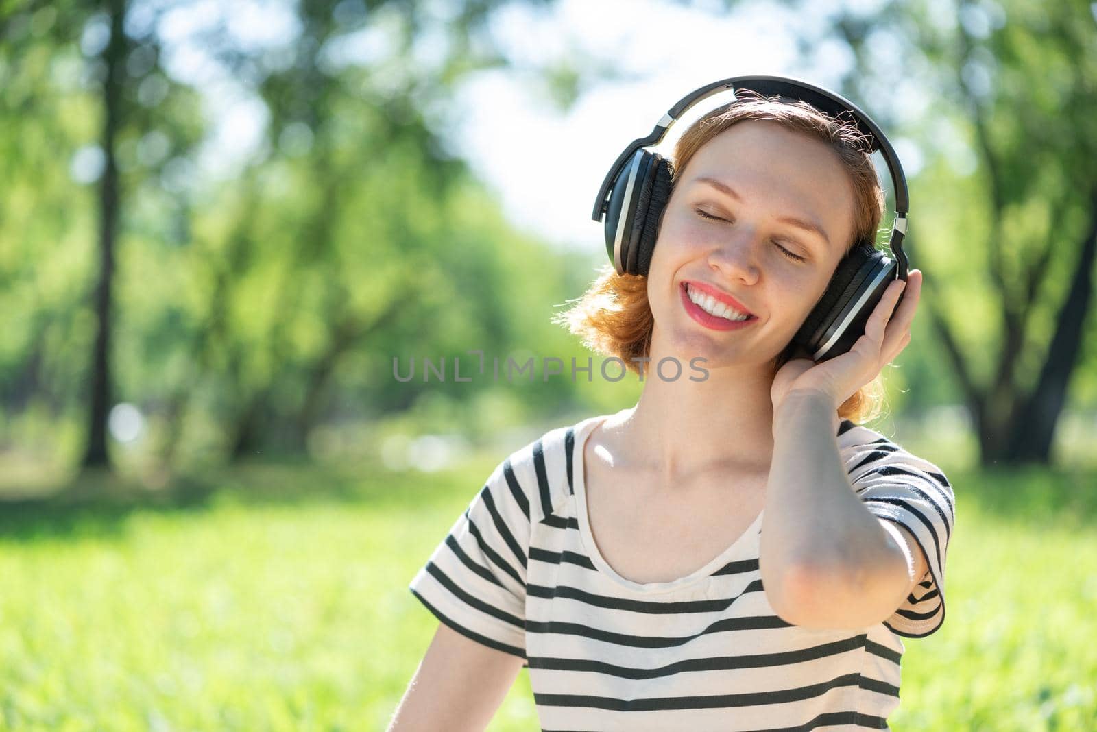 Young woman happens to have music in a summer park by adam121