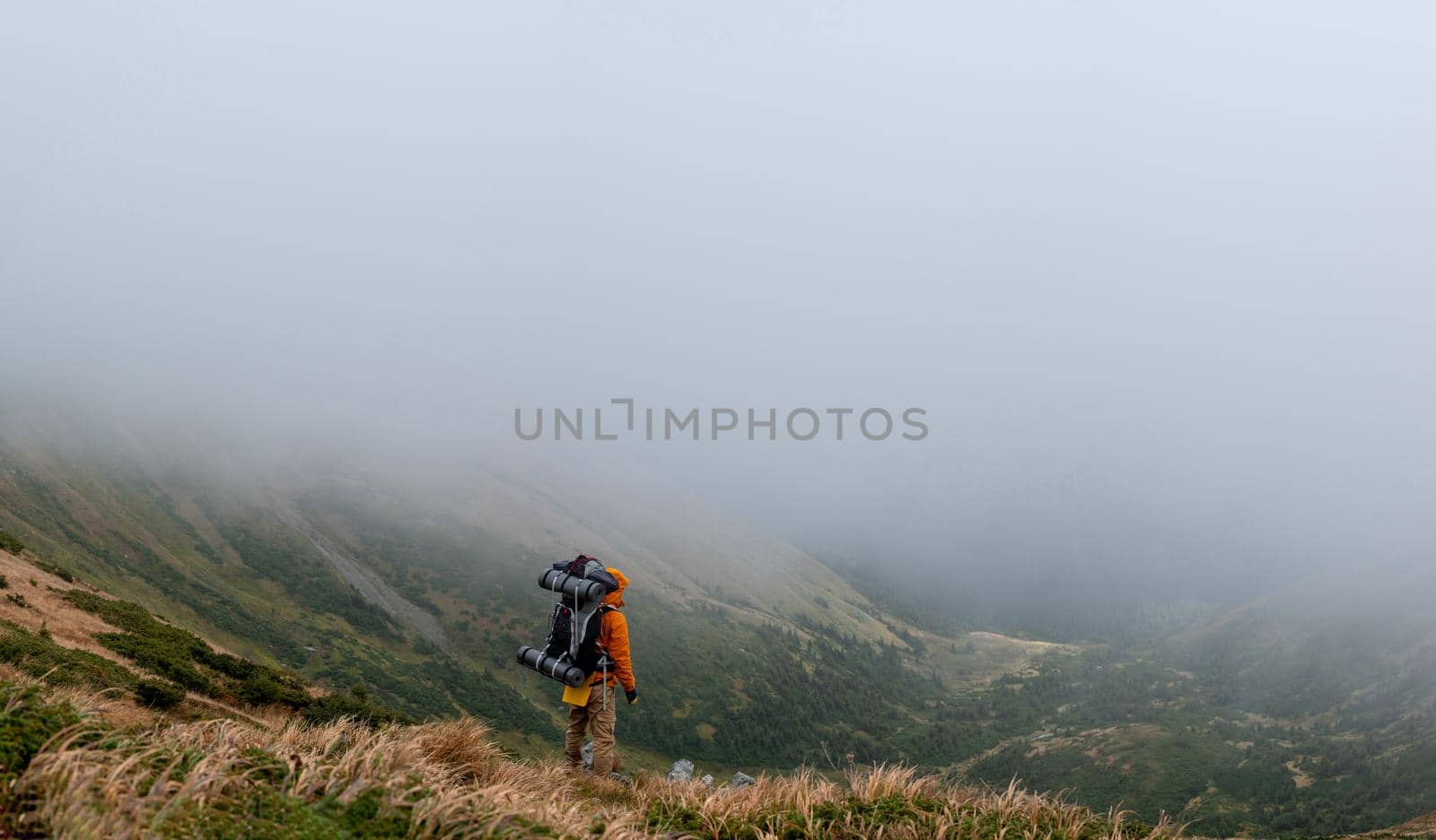 Tourist with a backpack on a background of picturesque Carpathians, picturesque autumn Carpathians, the tops of the Carpathian mountains in the clouds.