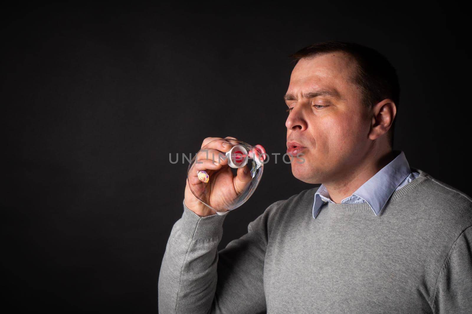 handsome man in a suit is blowing soap bubbles. isolated on a black background