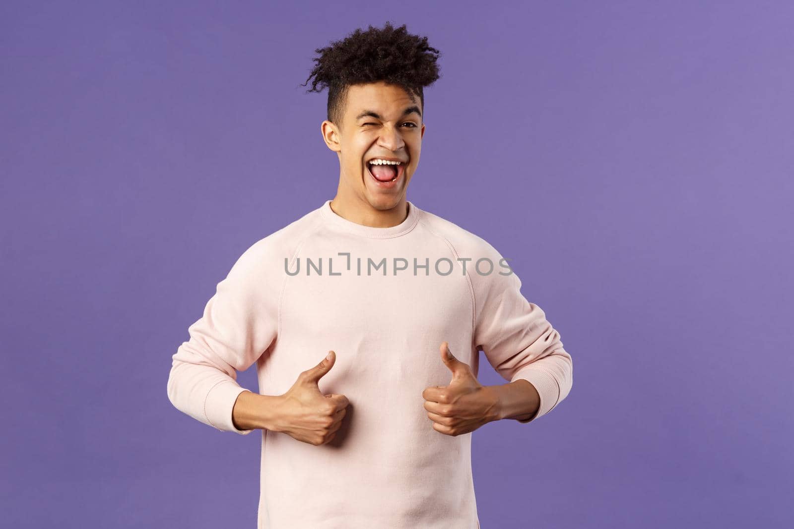 Portrait of enthusiastic lively, attractive young guy winking encourage join team, start career at this company, show thumbs-up with recommendation, give good advice, like and approve.