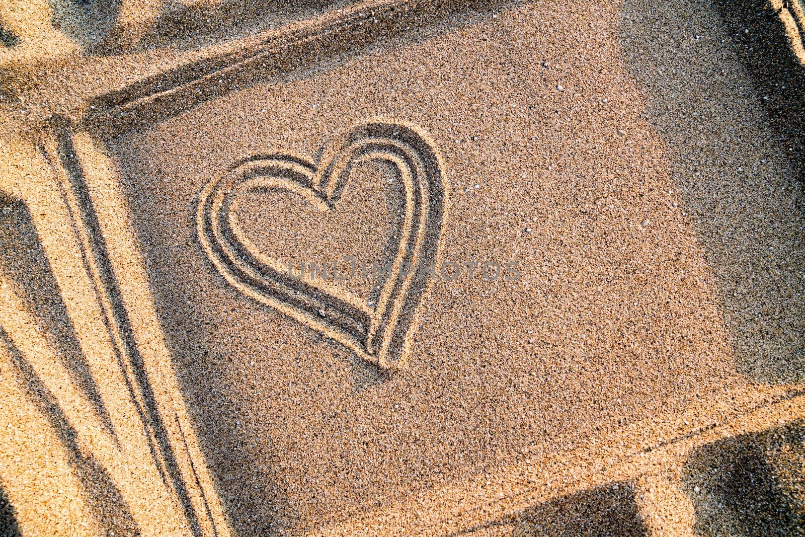 Heart drawn on the sand in a frame, close-up. Copy space. 
