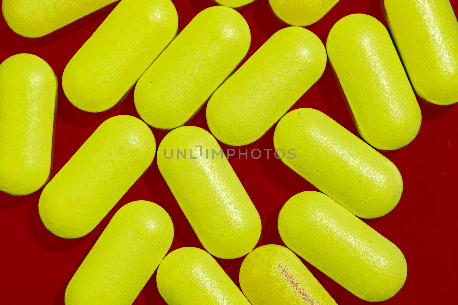 Yellow tablets capsules on dark red background. by Essffes