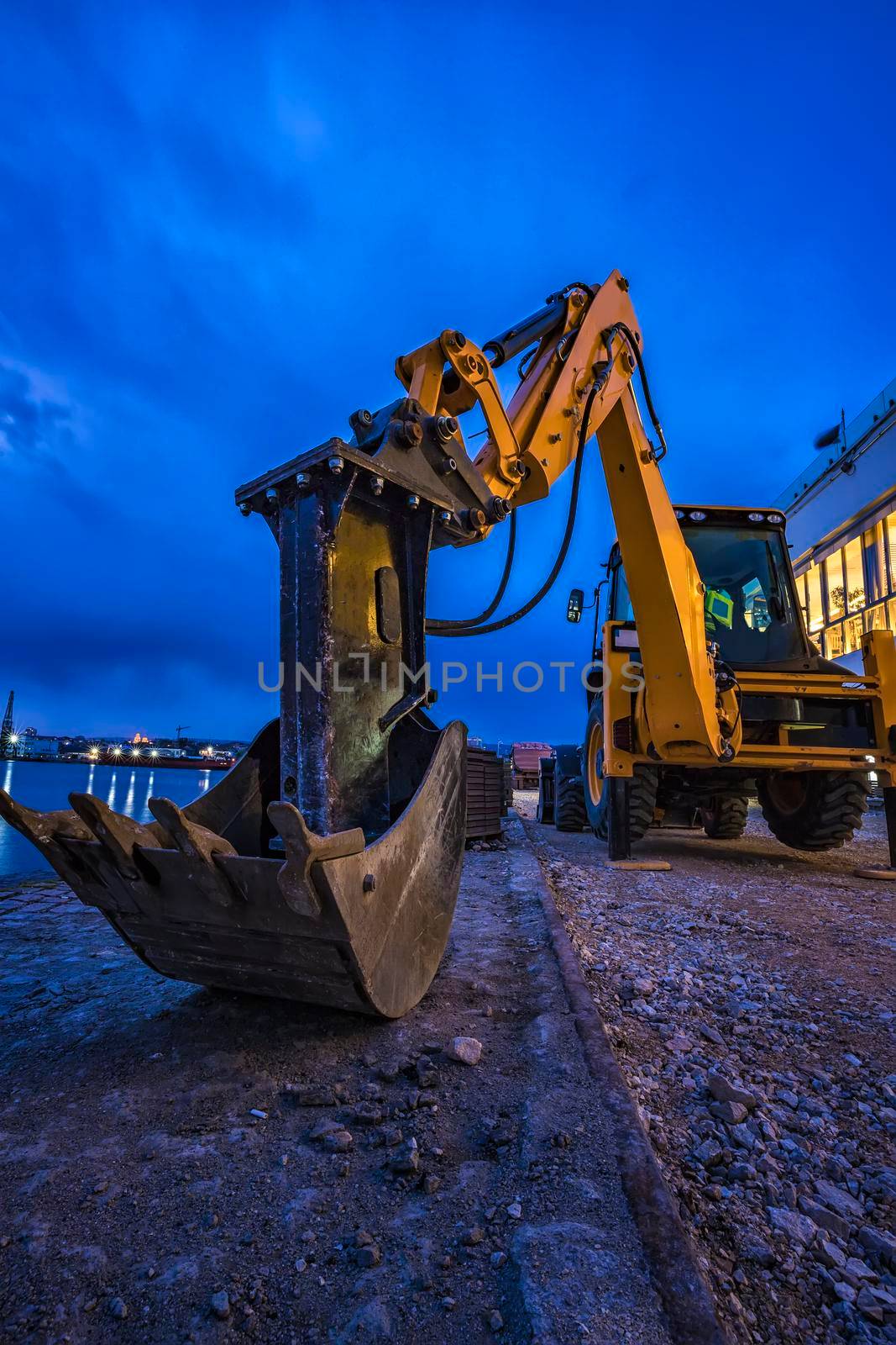 Big yellow stopped excavator at the construction site. Vertical view