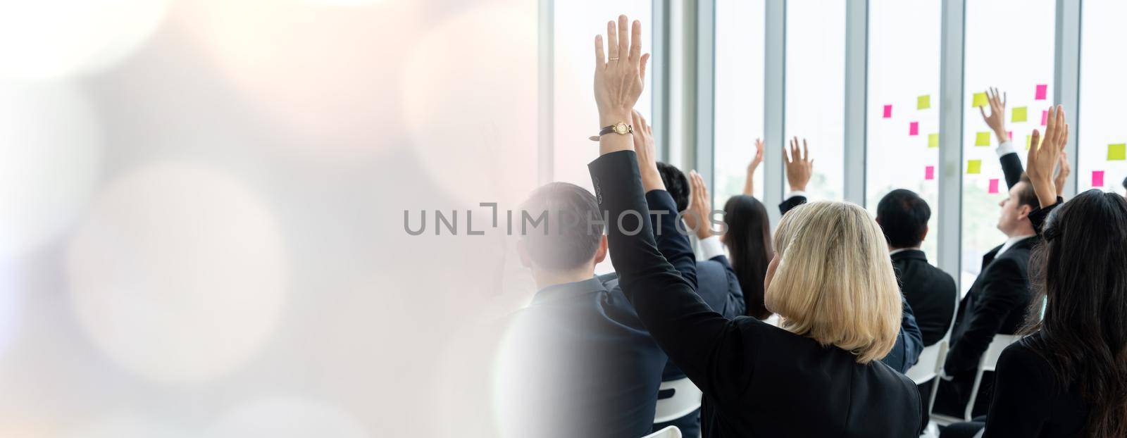 Group of business people meeting in a seminar conference widen view . Audience listening to instructor in employee education training session . Office worker community summit forum with speaker .