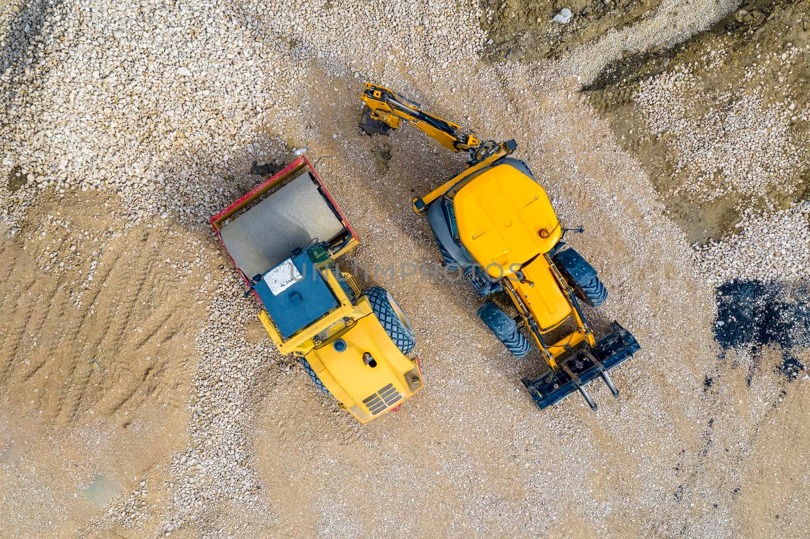 stunning aerial view of the stopped yellow excavator and drum roller at a construction site