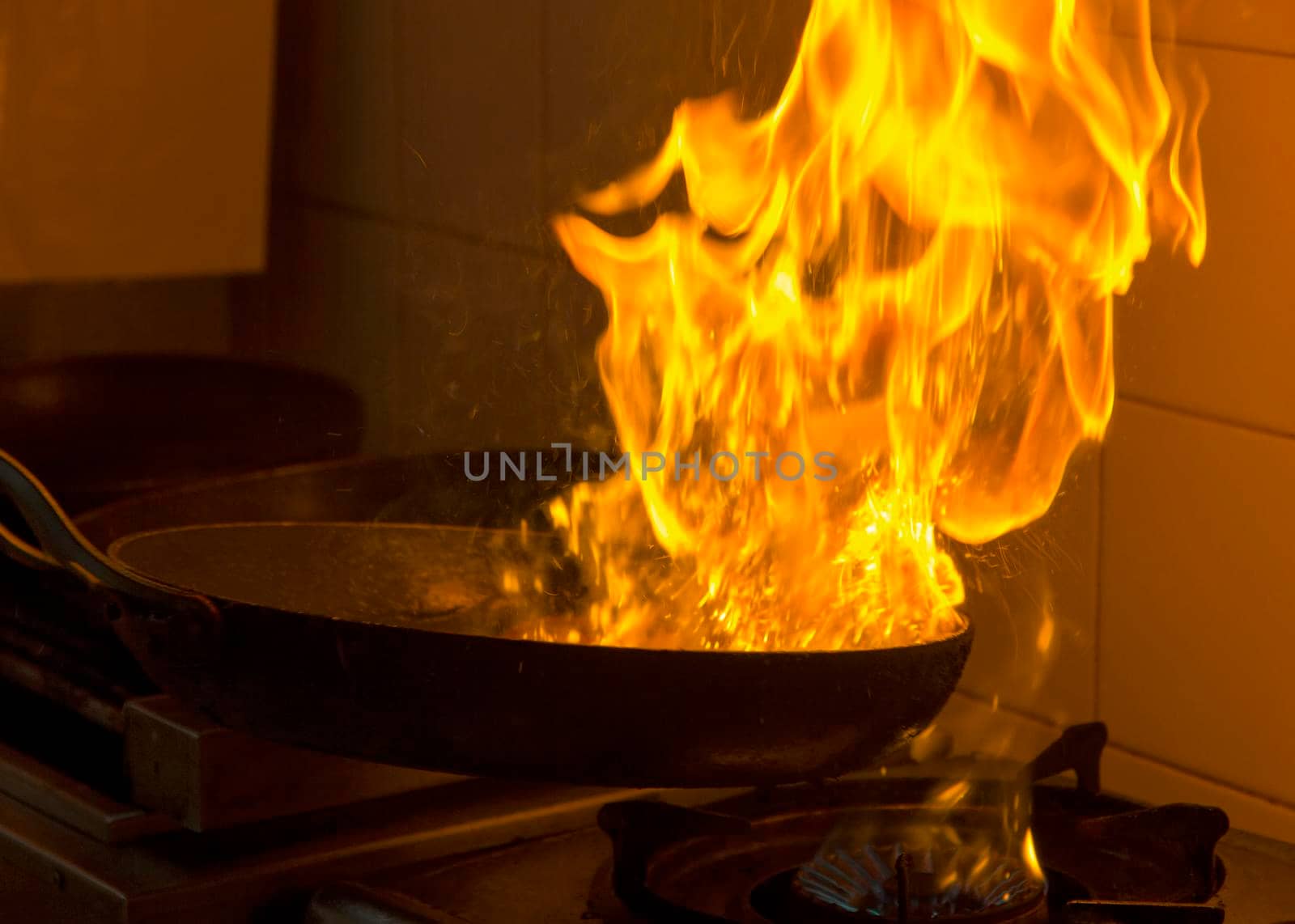 Chef cooking and doing flambe on food in a restaurant kitchen. Close up