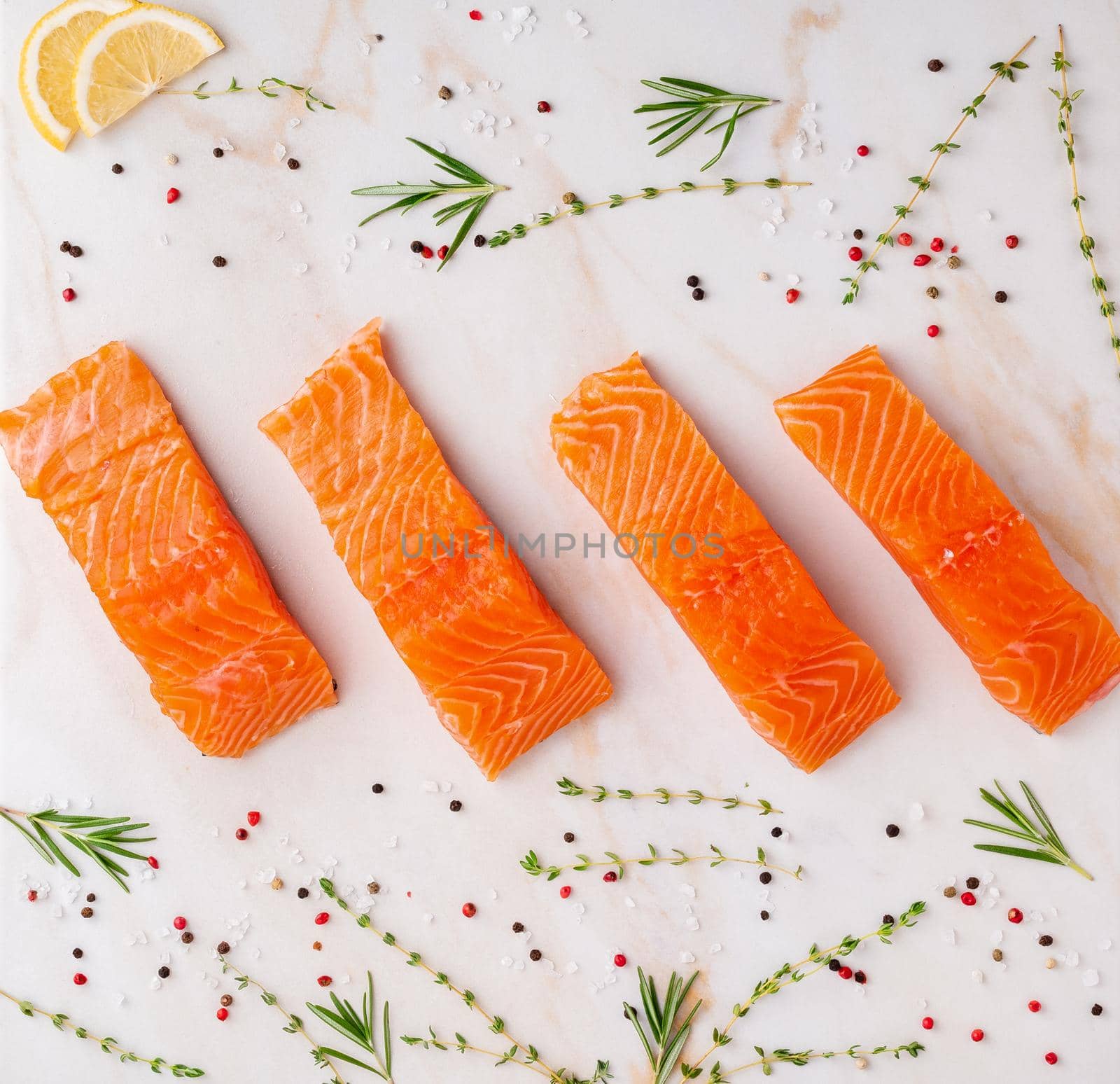 Food background, sliced portions large salmon fillet steaks and seasonings on white cream marble table, flat lay.