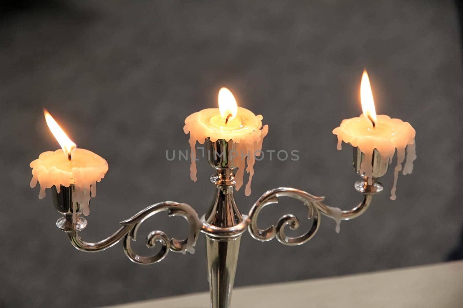 Vintage candlestick with three burning candles. Horizontal view.