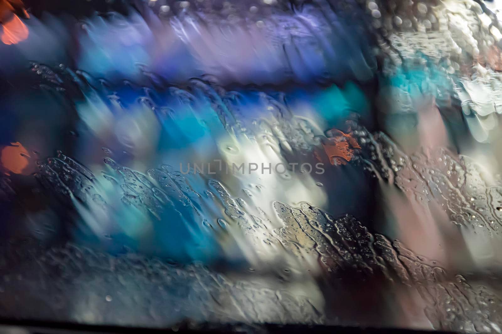 Raindrops on the window. Water drops on glass. The surface of wet glass. City lights bokeh during the rain.