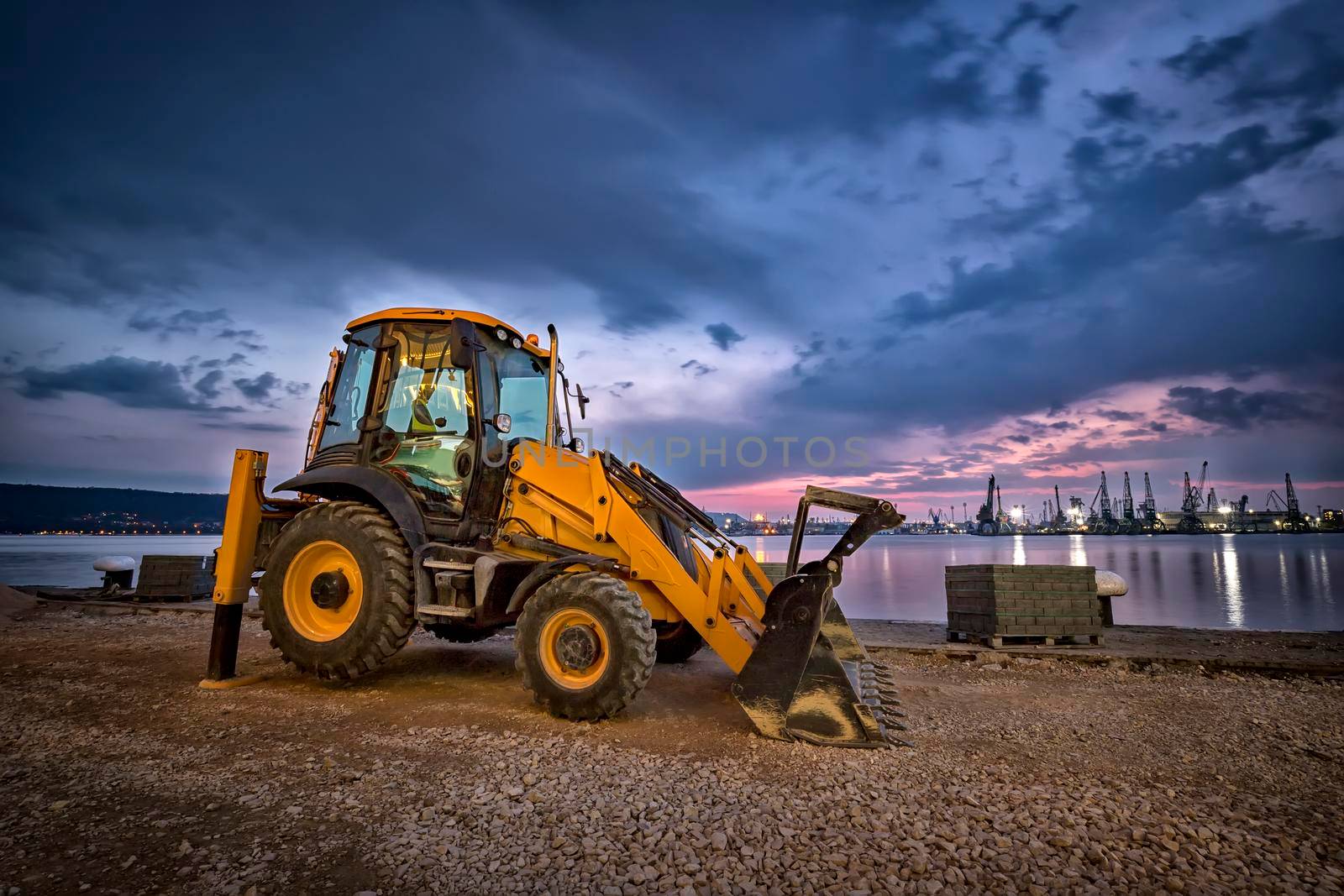 Amazing view at yellow excavator with a shovel at a construction site in a beautiful twilight
