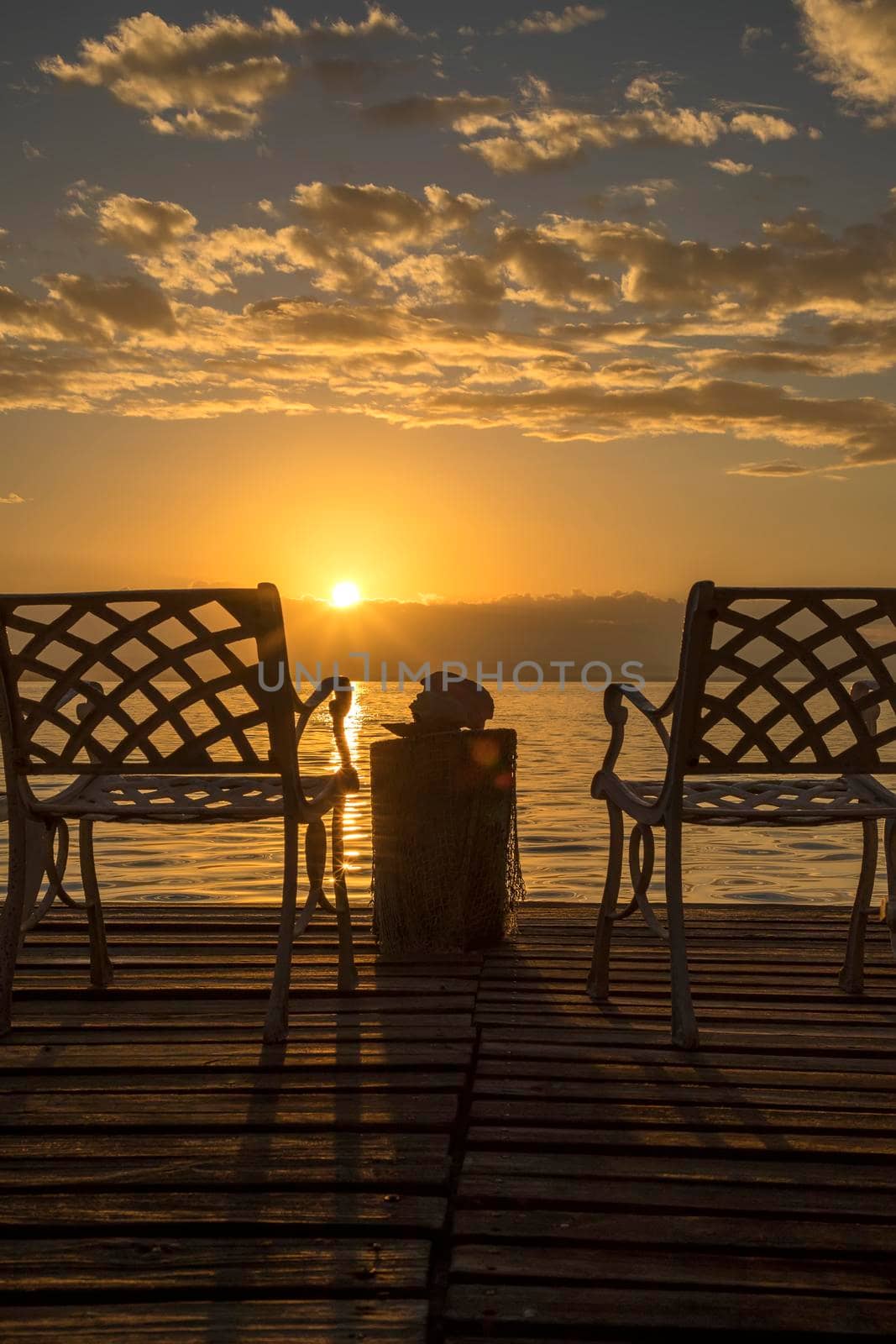 Two empty chairs at sunrise on the sea beach. Vertical view.