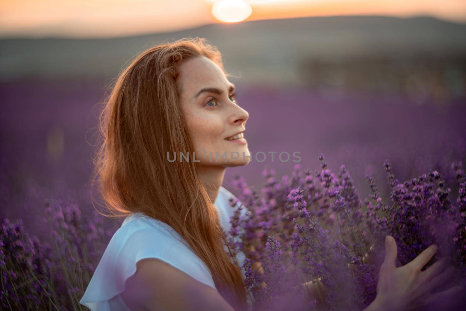 Beautiful girl on the lavender field. Beautiful woman in the lavender field on sunset. Soft focus.