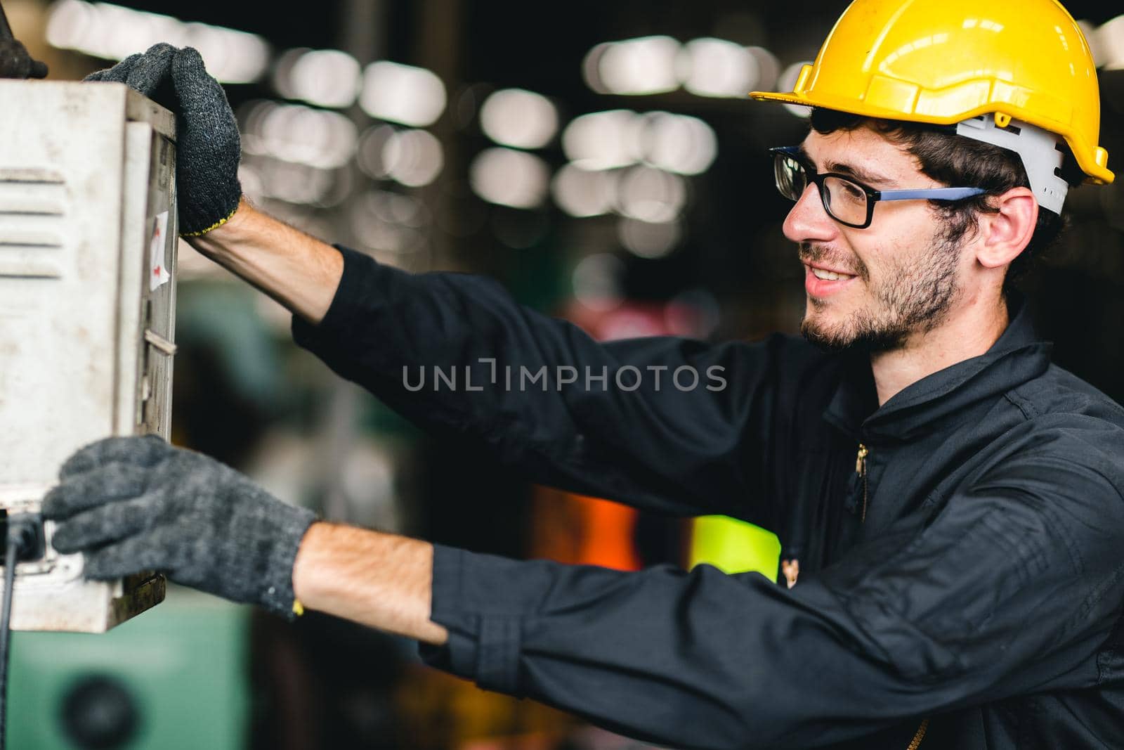 young American worker happy working to control machine,he enjoy smiling at heavy industrial factory.