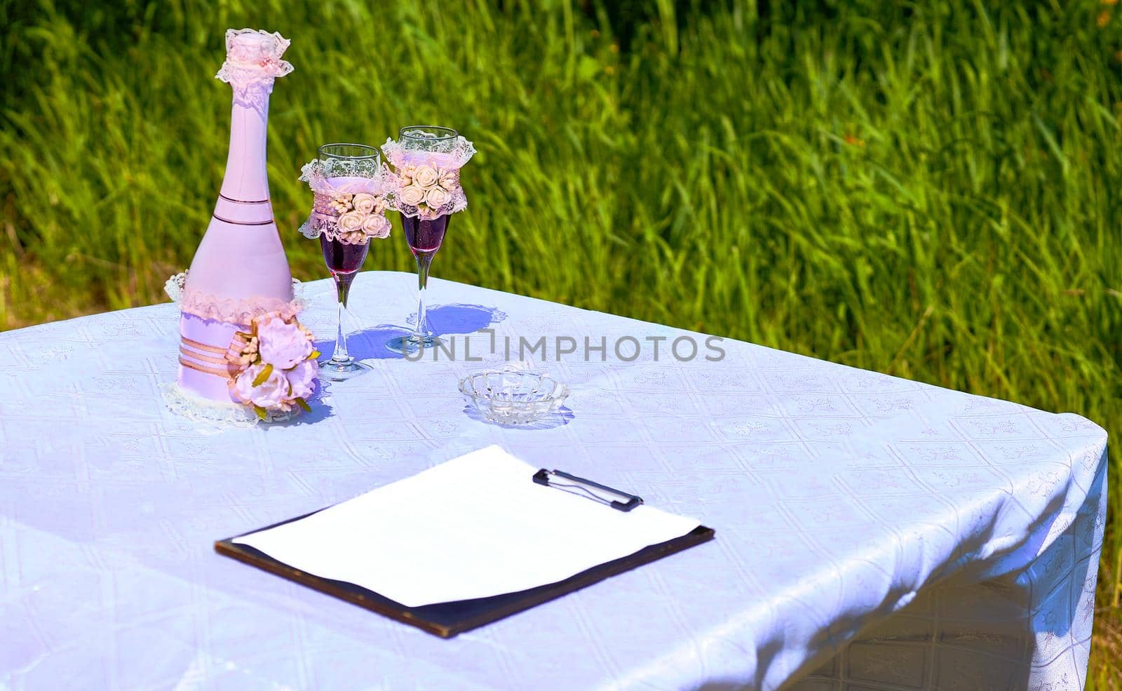 Wedding accessories and champagne with glasses for marriage in summer park by jovani68