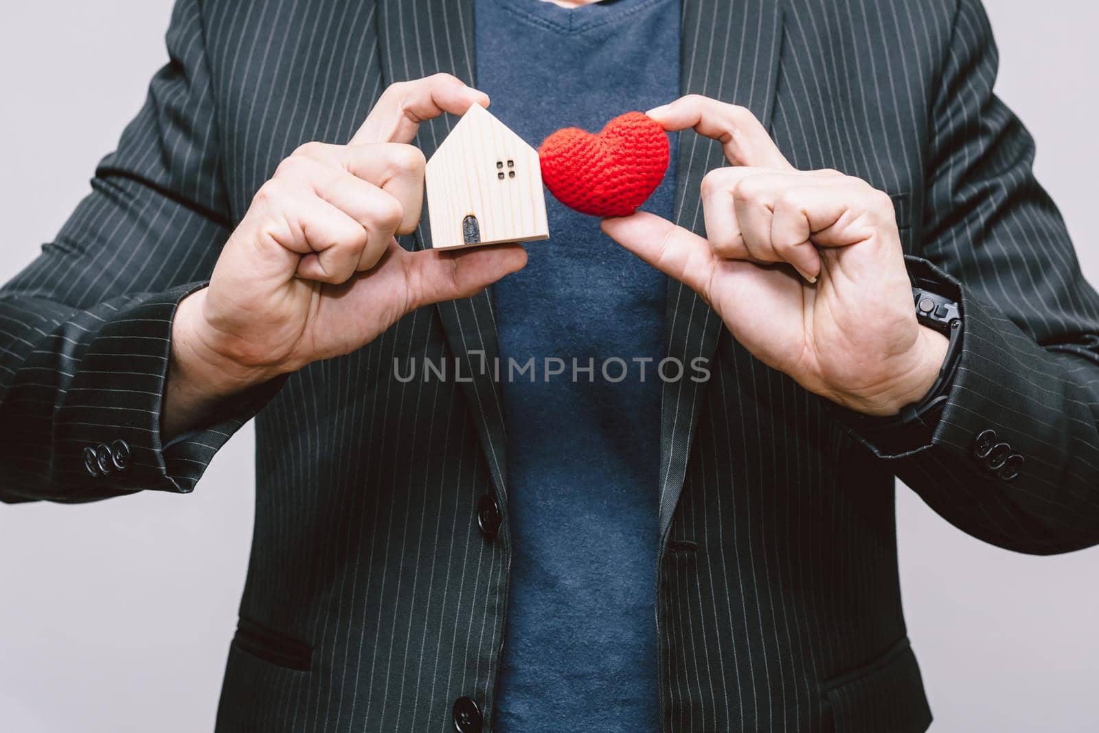 Business man handle home and red heart for Stay Home or love care people in the house family concept. by qualitystocks