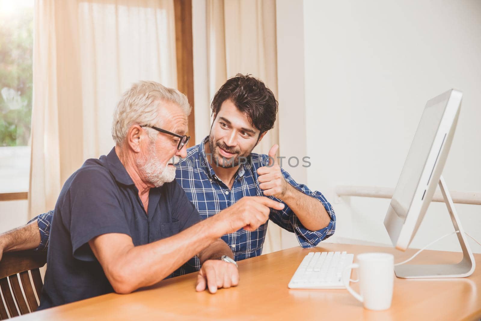 young man or son teaching his grandfather elderly dad learning to using computer at home. by qualitystocks