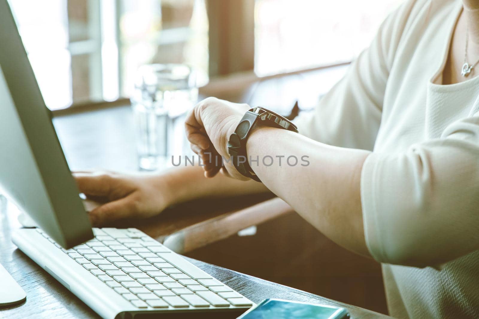 Businesswoman working on desk looking check meeting time on her wrist watch for schedule remind. by qualitystocks