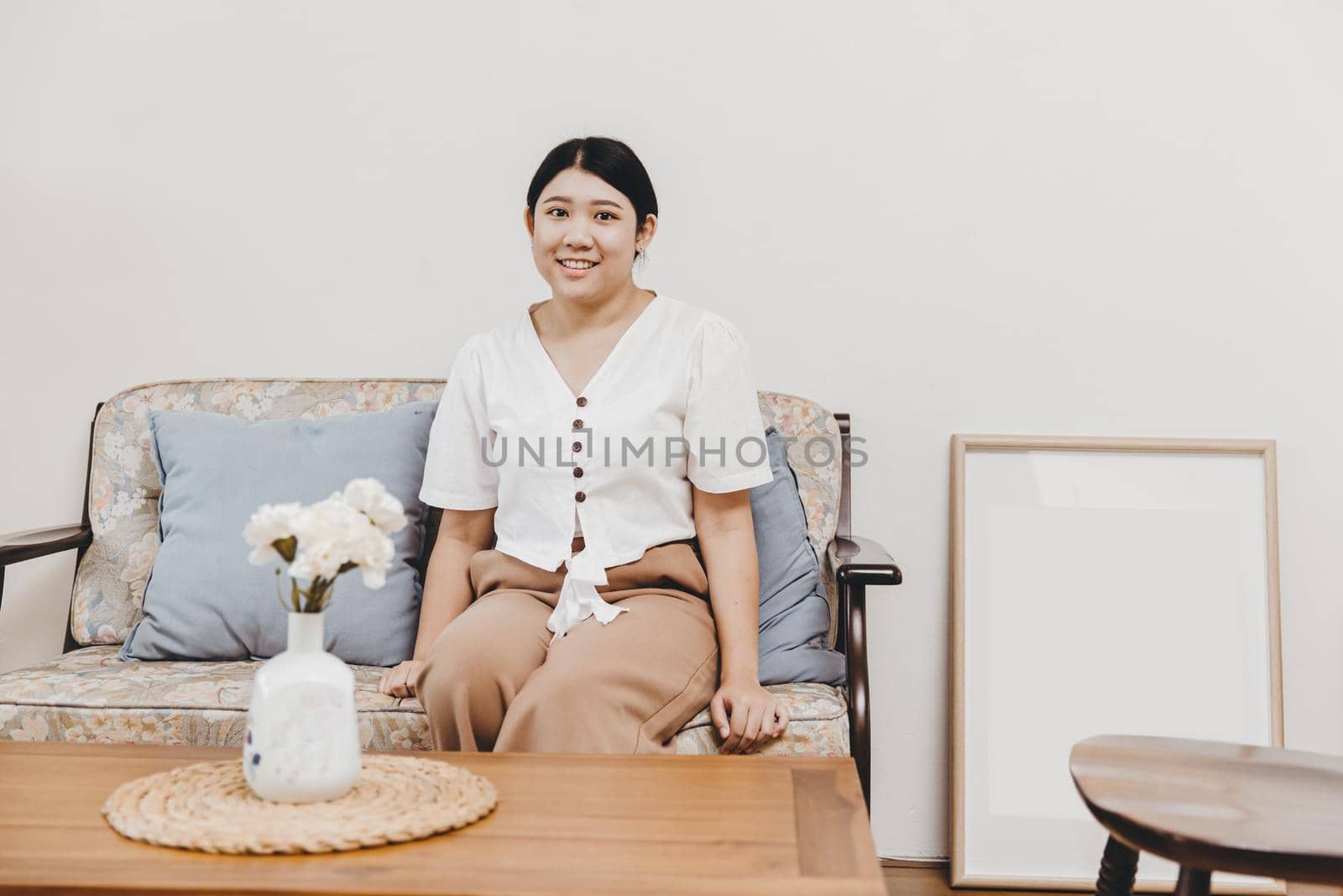 Plump and healthy housewife sitting in the home living room warm smiling, looking at the camera