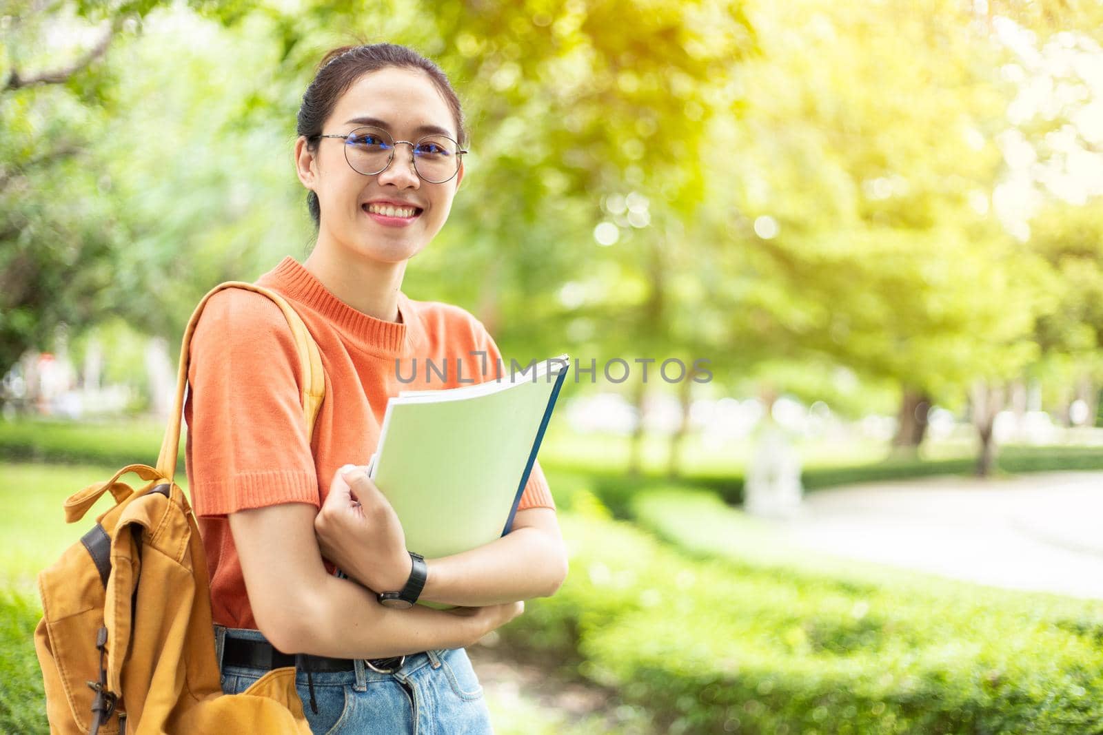 Portrait of nerd Asian woman girl smart teen happy smiling with glasses at green park outdoor in university campus with copyspace by qualitystocks