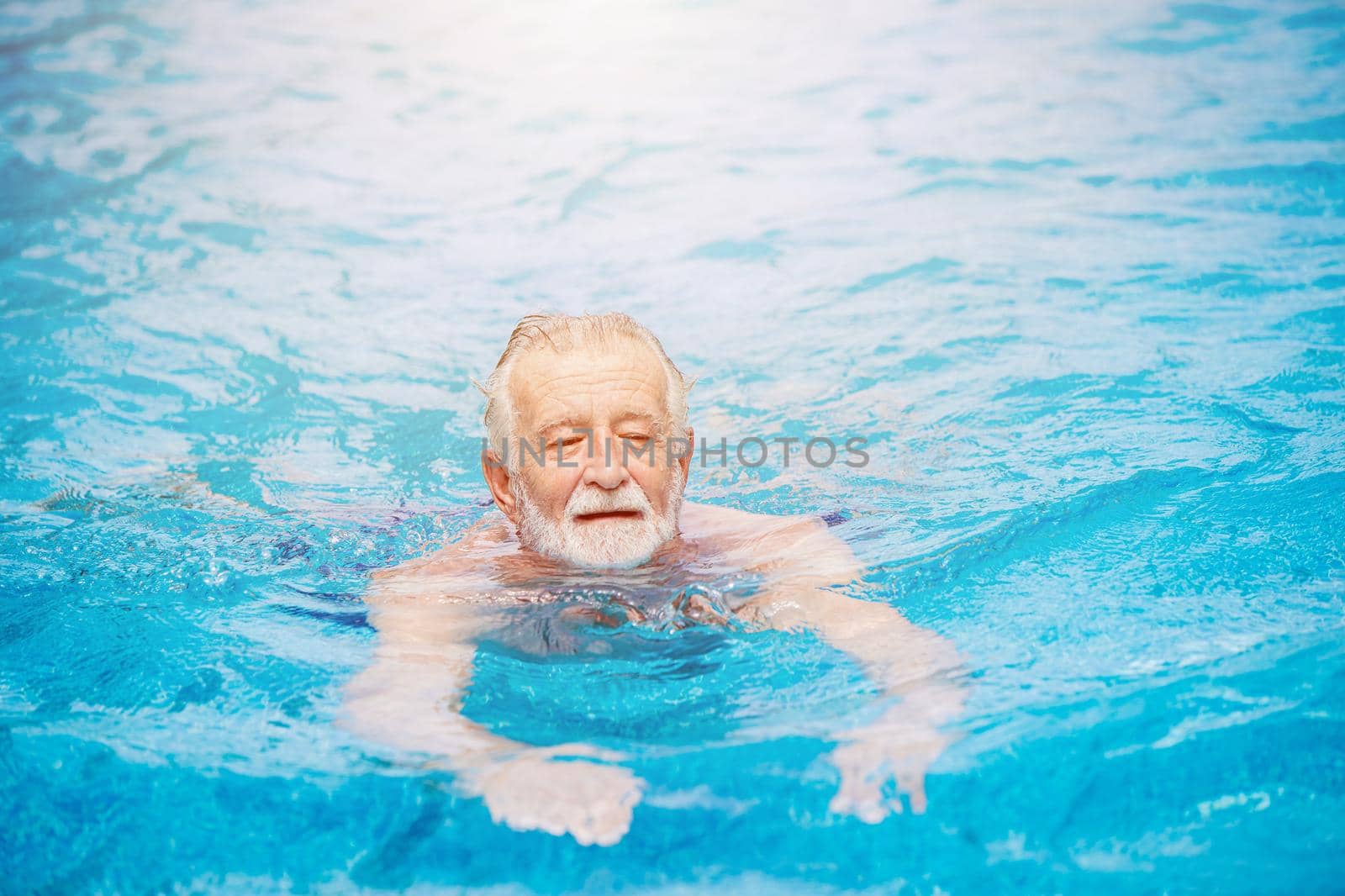 Caucasian healthy elder swimming at the swimming pool for relax in summer holiday activity by qualitystocks