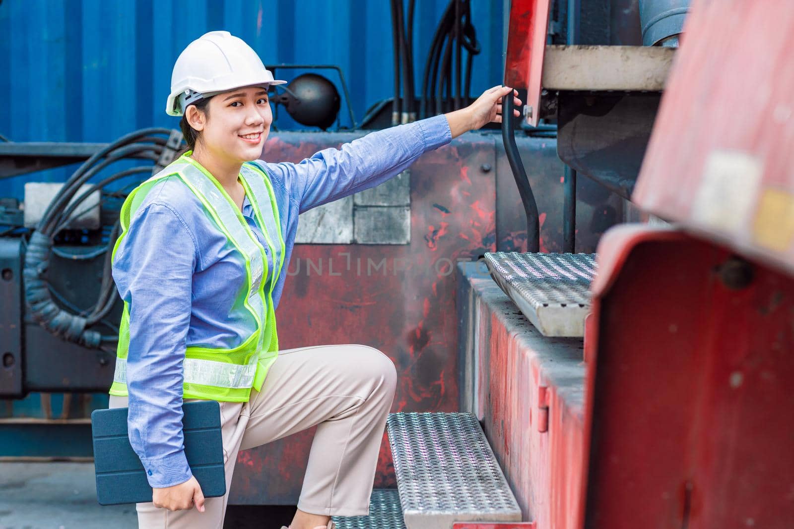Asian young teen happy smile engineer worker working with heavy industry machine with safety suit and hardhat, looking camera. by qualitystocks