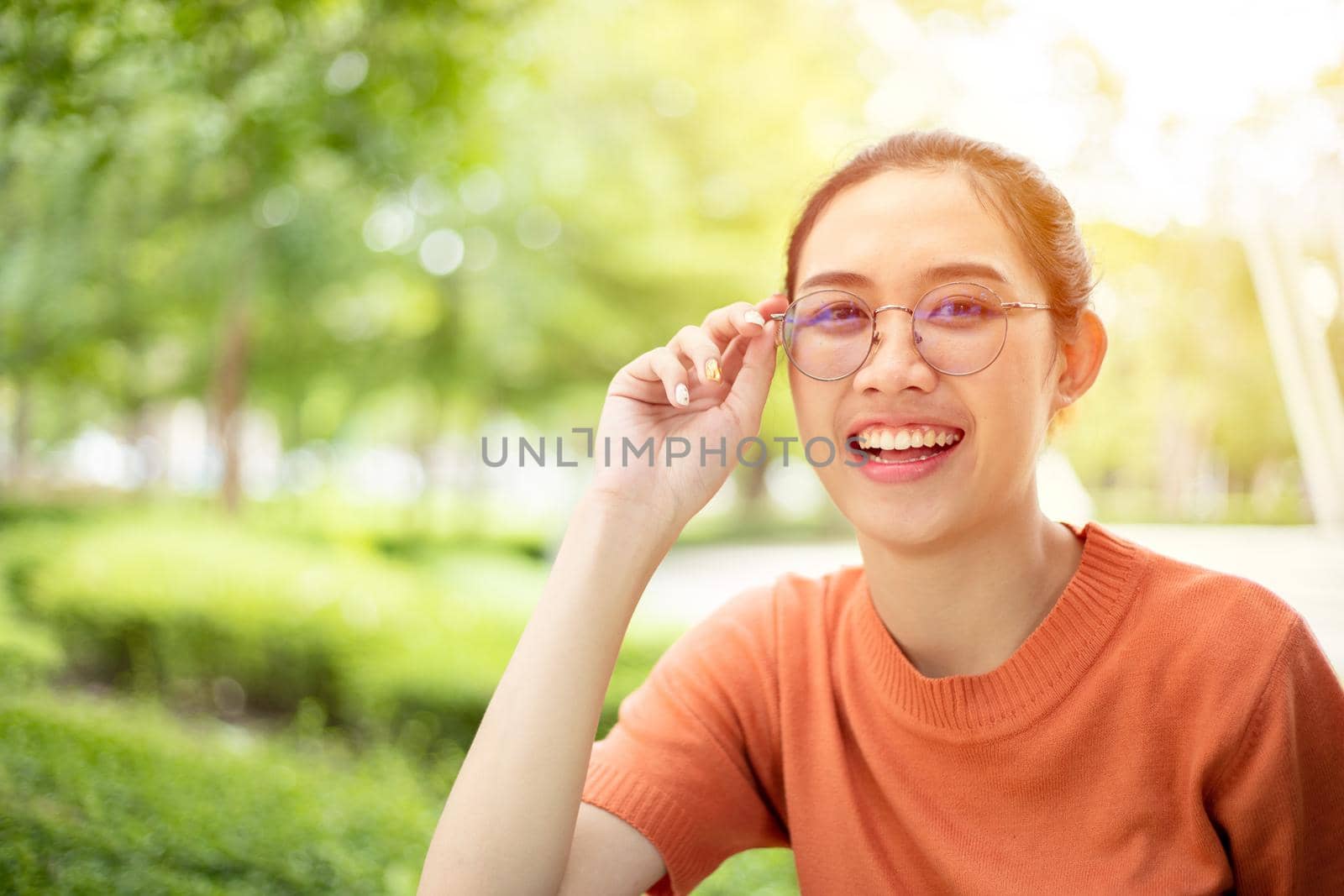 Asian woman wearing glasses happy smile with green nature outdoor background by qualitystocks