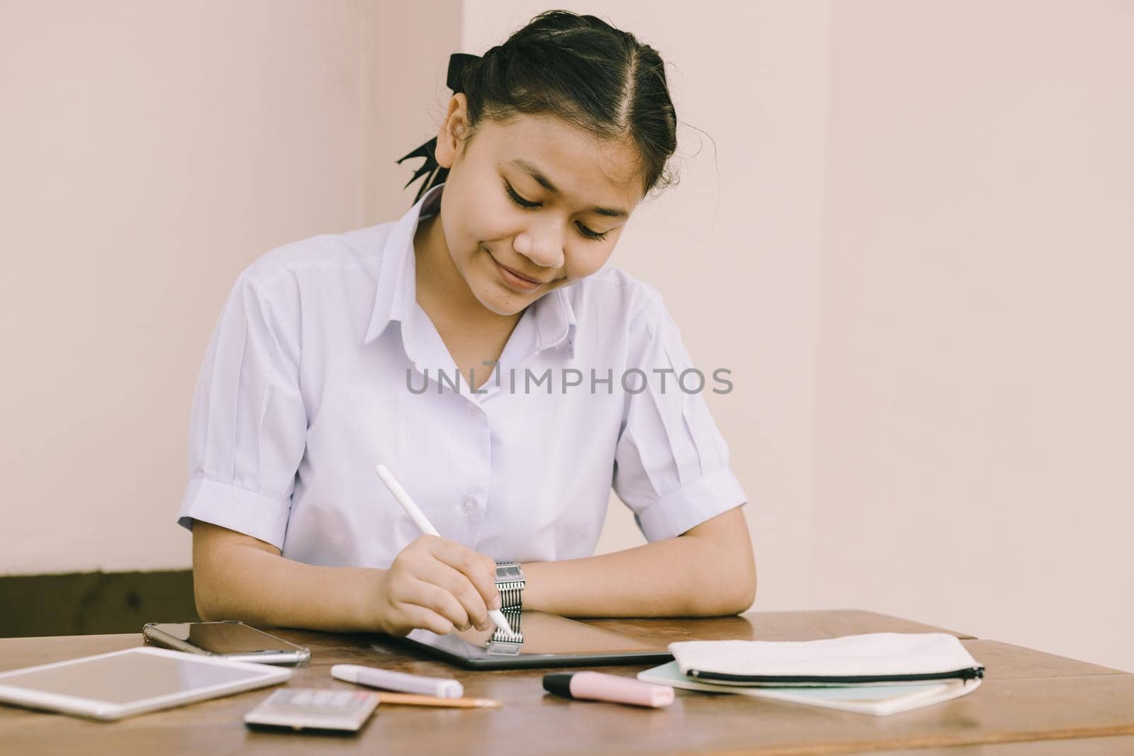 Asian Thai cute girl teen student school uniform happy smile using Tablet PC for homework and E-Learning self isolated education happy smile concept