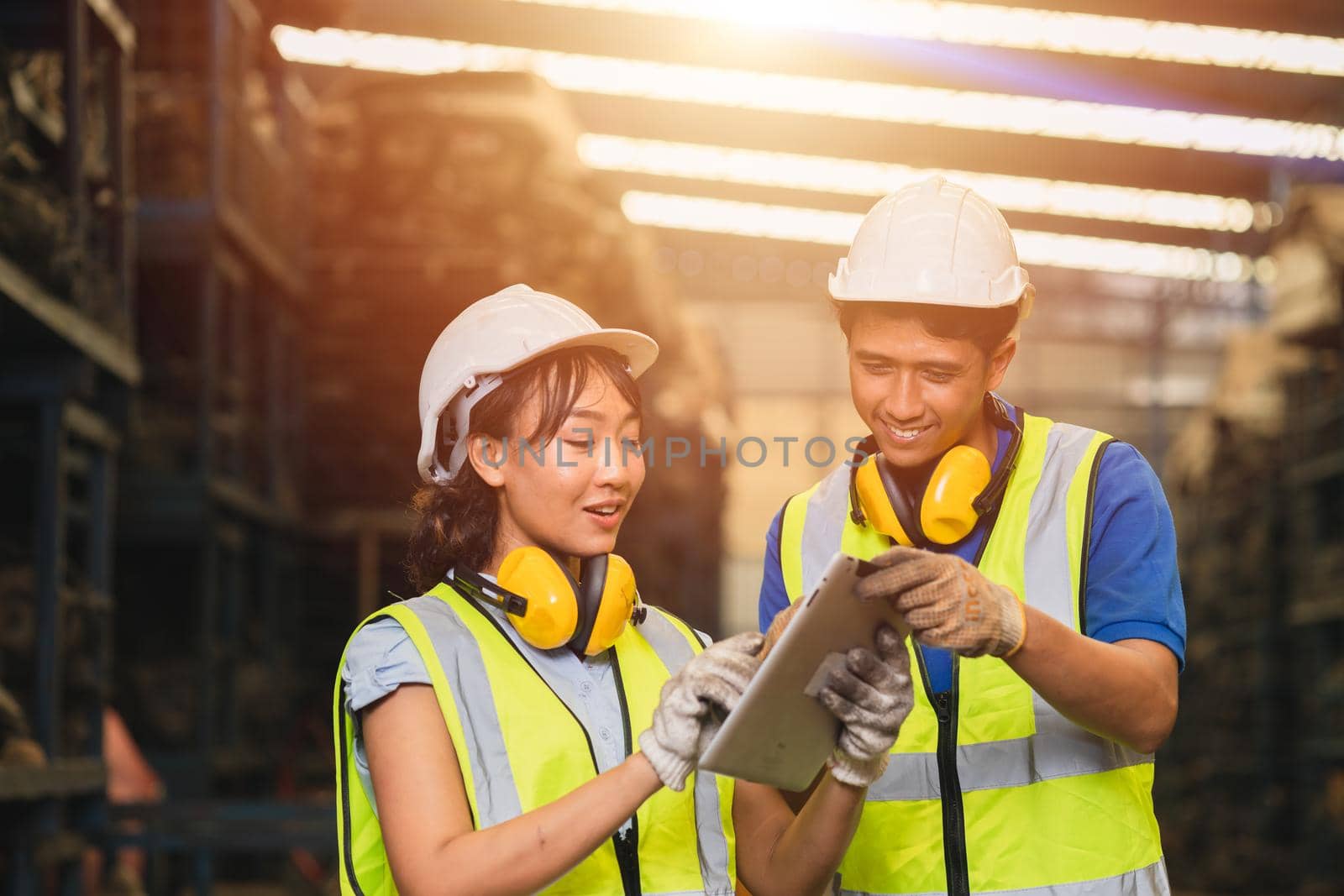 Asian young man and women worker team engineer working help support together using tablet happy smile to work in factory industry