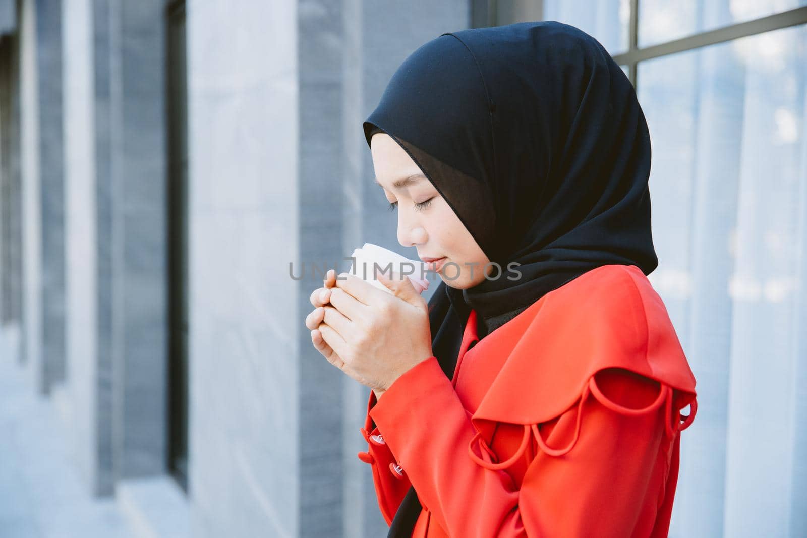 Arab Muslim women drinking coffee in the morning outdoor, Asian businesswoman young girl smiling hand hold coffee cup standing closeup.