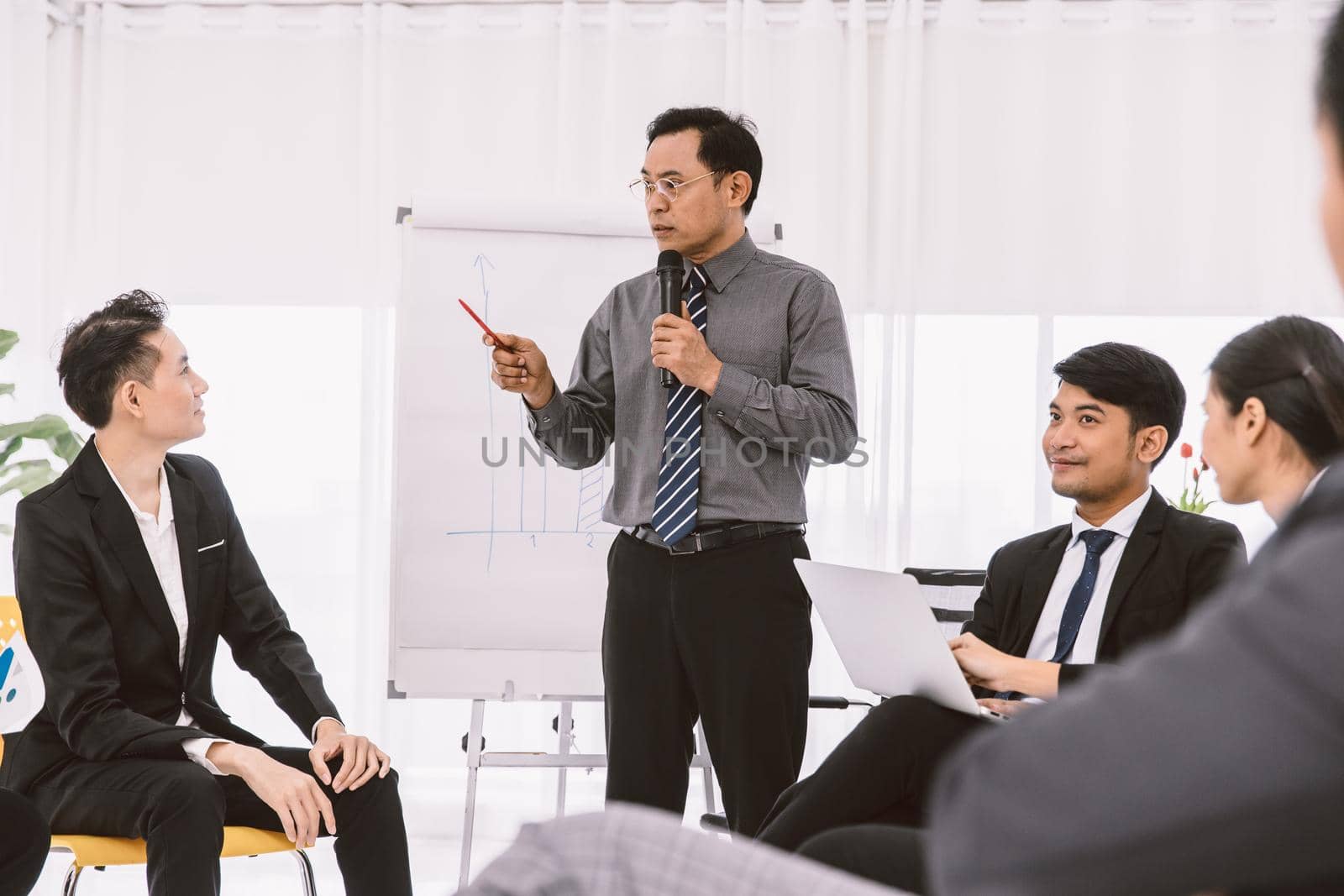 Asian businessman meeting or company conference sale report target discussion. Professional manager talking to young new staff for business planning and training.