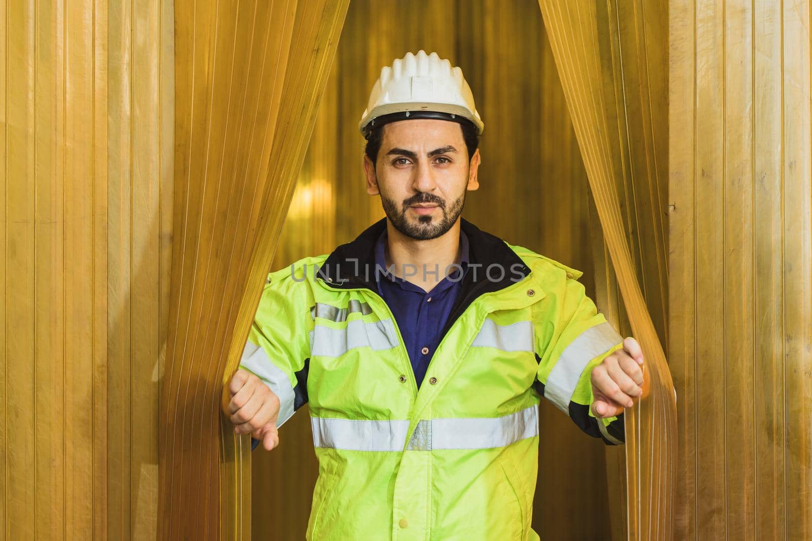 Portrait confidence handsome latin engineer worker man opening yellow pvc curtain in a food factory by qualitystocks
