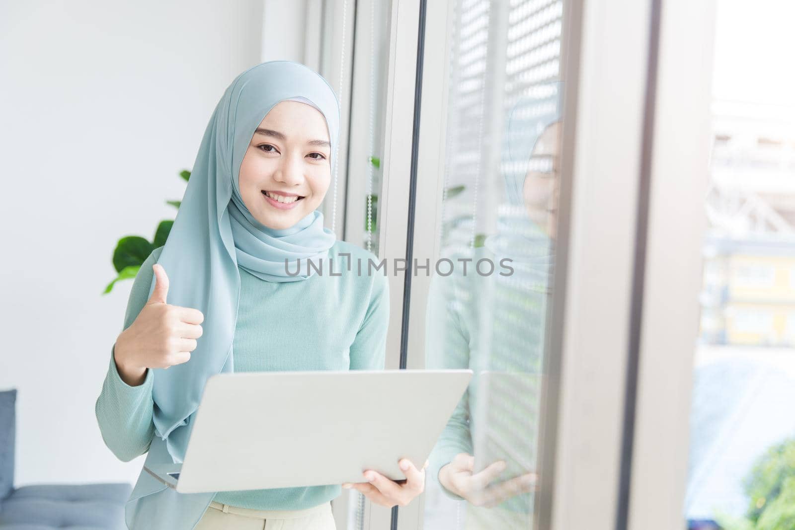 Asian Muslim Islamic woman with hijab happy enjoy working in office with laptop computer.