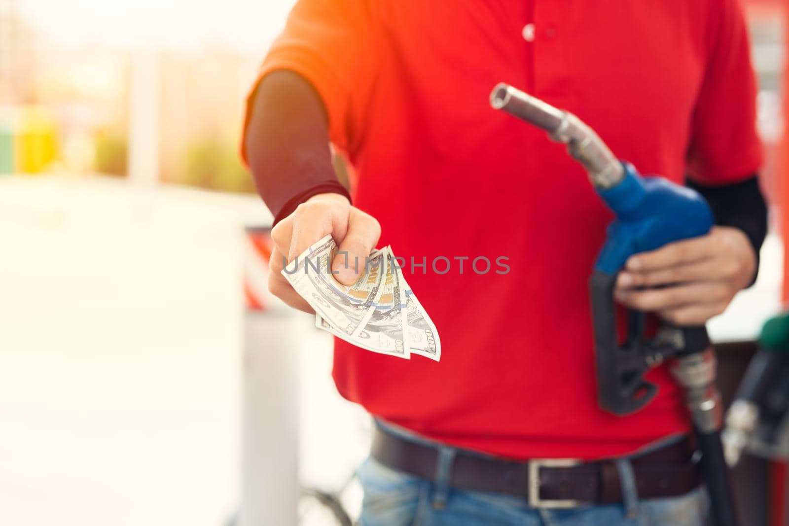 Gas station staff worker return the money back for lower fuel price, gas costs reduction, cut saving gasoline drop price and pay cash back concept by qualitystocks
