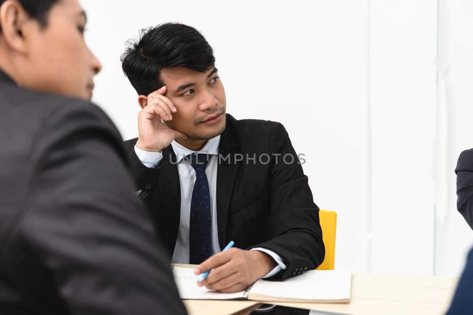 Businessman attend a meeting listening with intend bore and serious mood.Asian Business male boring at work in office seminar.