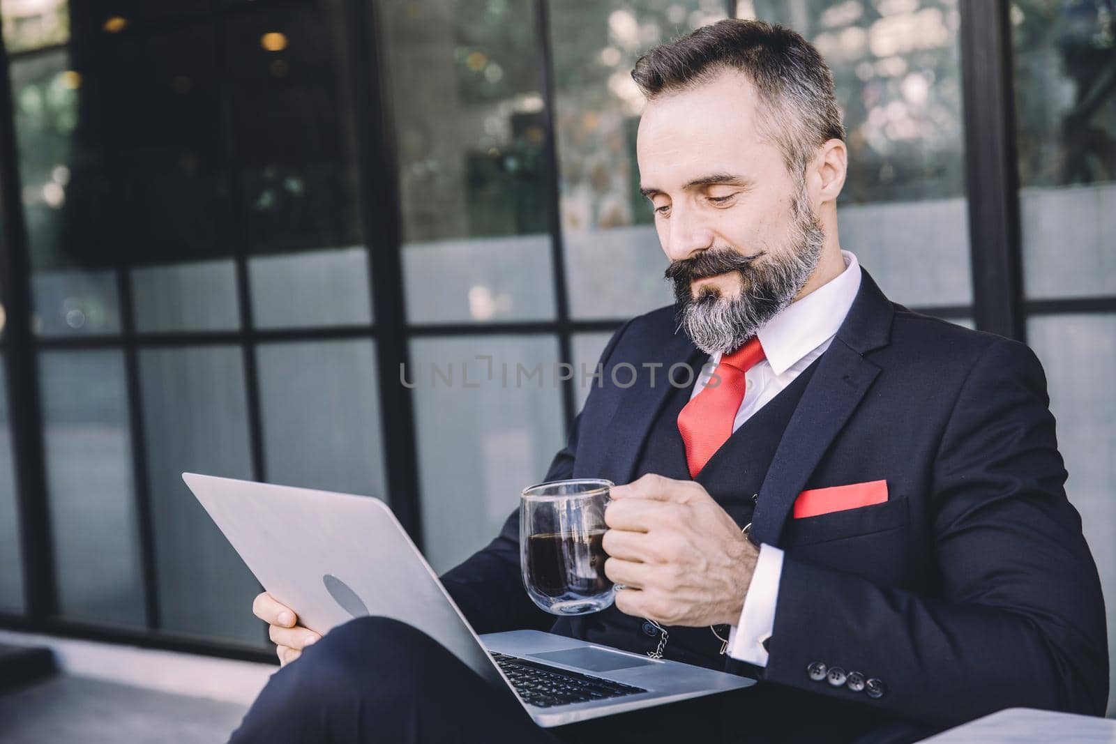 Hispanic latin businessman beard happy enjoy working with laptop computer relax at cafe drinking hot coffee by qualitystocks