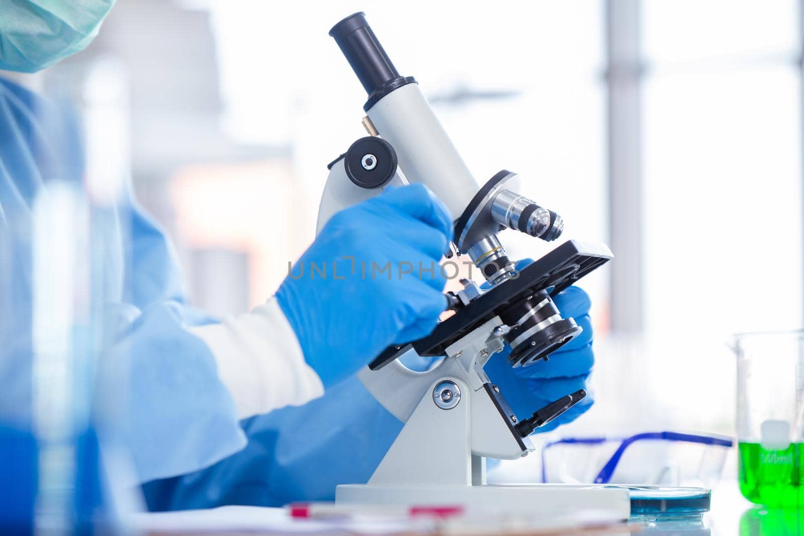 Closeup Scientist Doctor working in medical healthcare lab for medicine research looking at microscope. science covid virus vaccine research medical concept. by qualitystocks