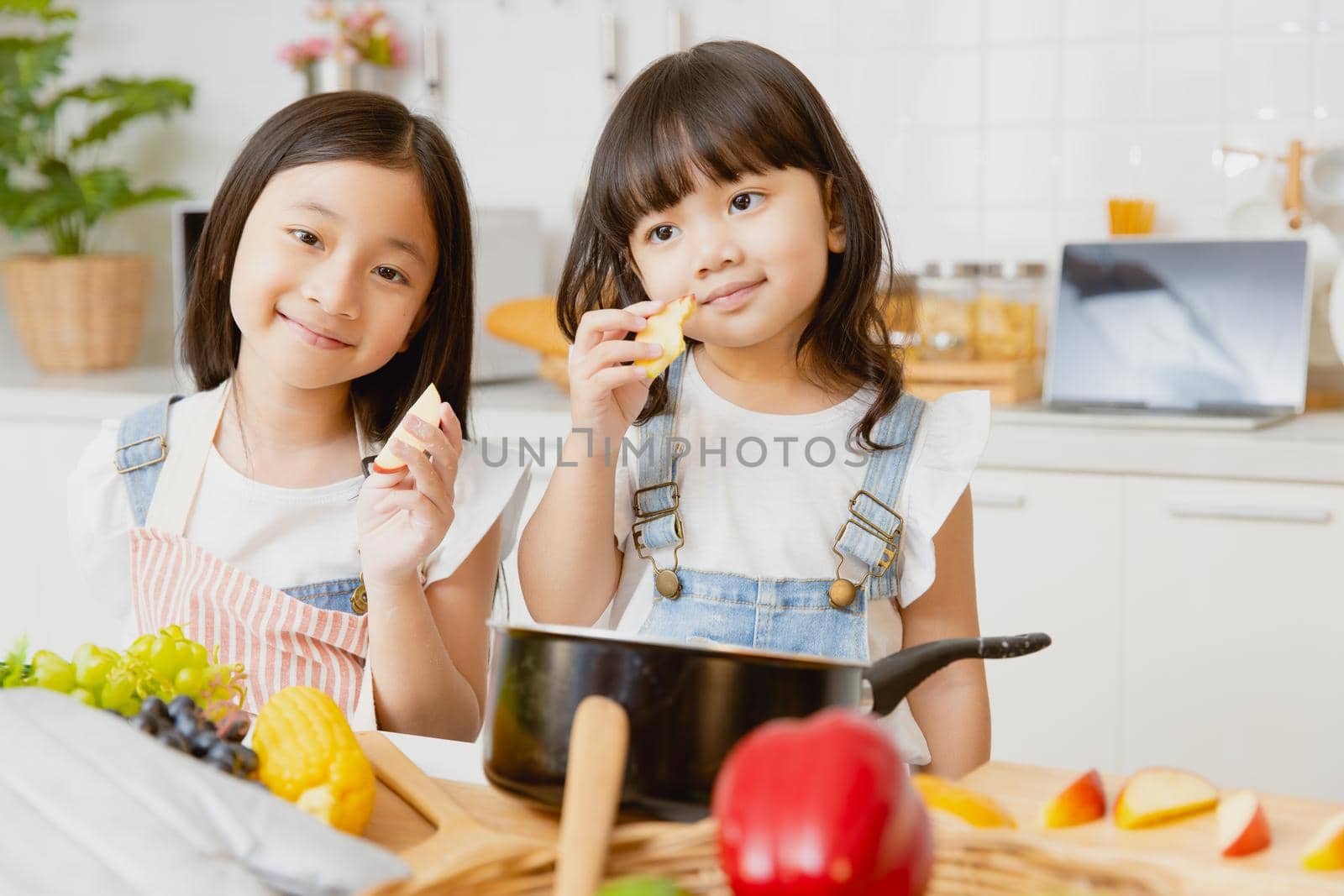 portrait healthy girl childs happy playing together in the kitchen eating apple fruit by qualitystocks