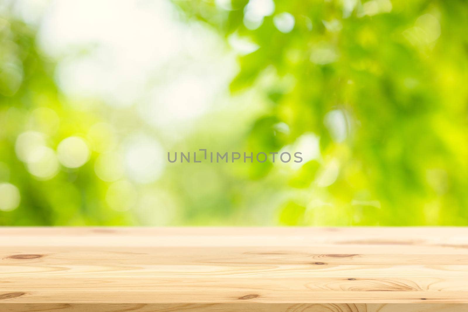 Blur green garden nature background with wooden table space for products advertising montage overlay template.