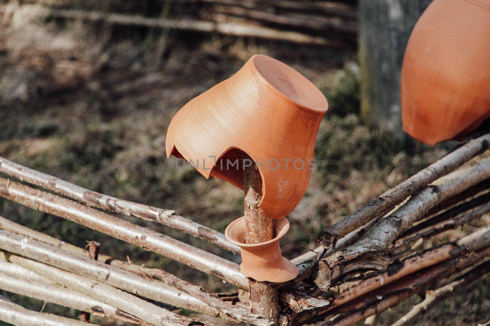 The remains of an old clay pot hang on a wicker fence . High quality photo