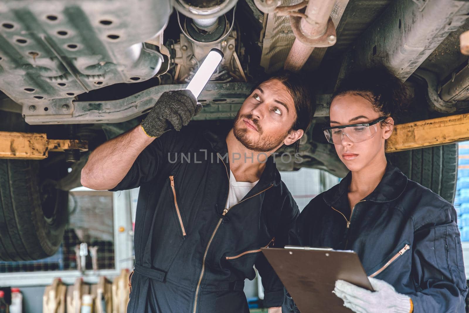 Auto mechanic team working help support together to checking under car for service maintenance in garage