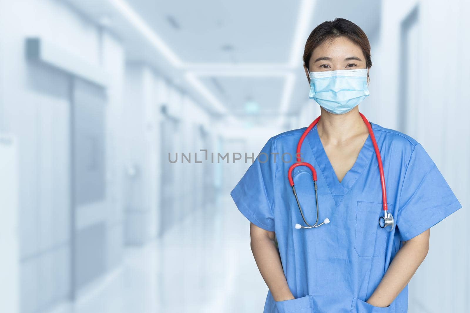 Portrait Asian Doctor or Nurse with mask standing in blur hospital background copy space