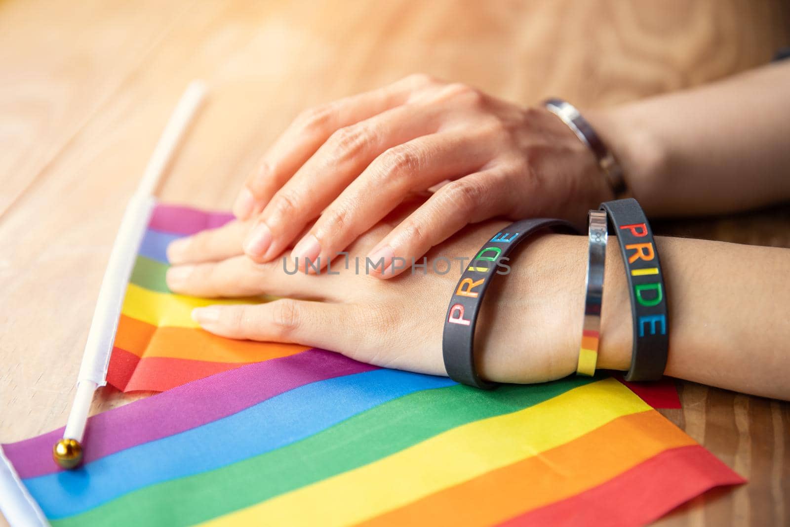 Transgender people hand together with LGBT rainbow flag for sexuality rights campaign symbol by qualitystocks