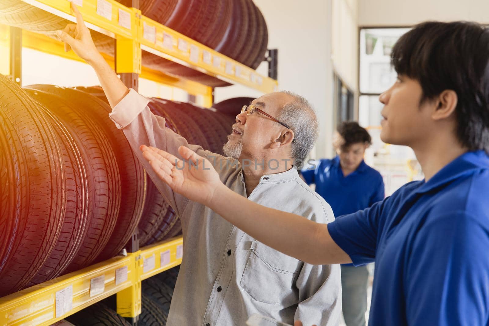 Customer selecting car tyres in garage and sale staff recommend various types of vehicle tires by qualitystocks