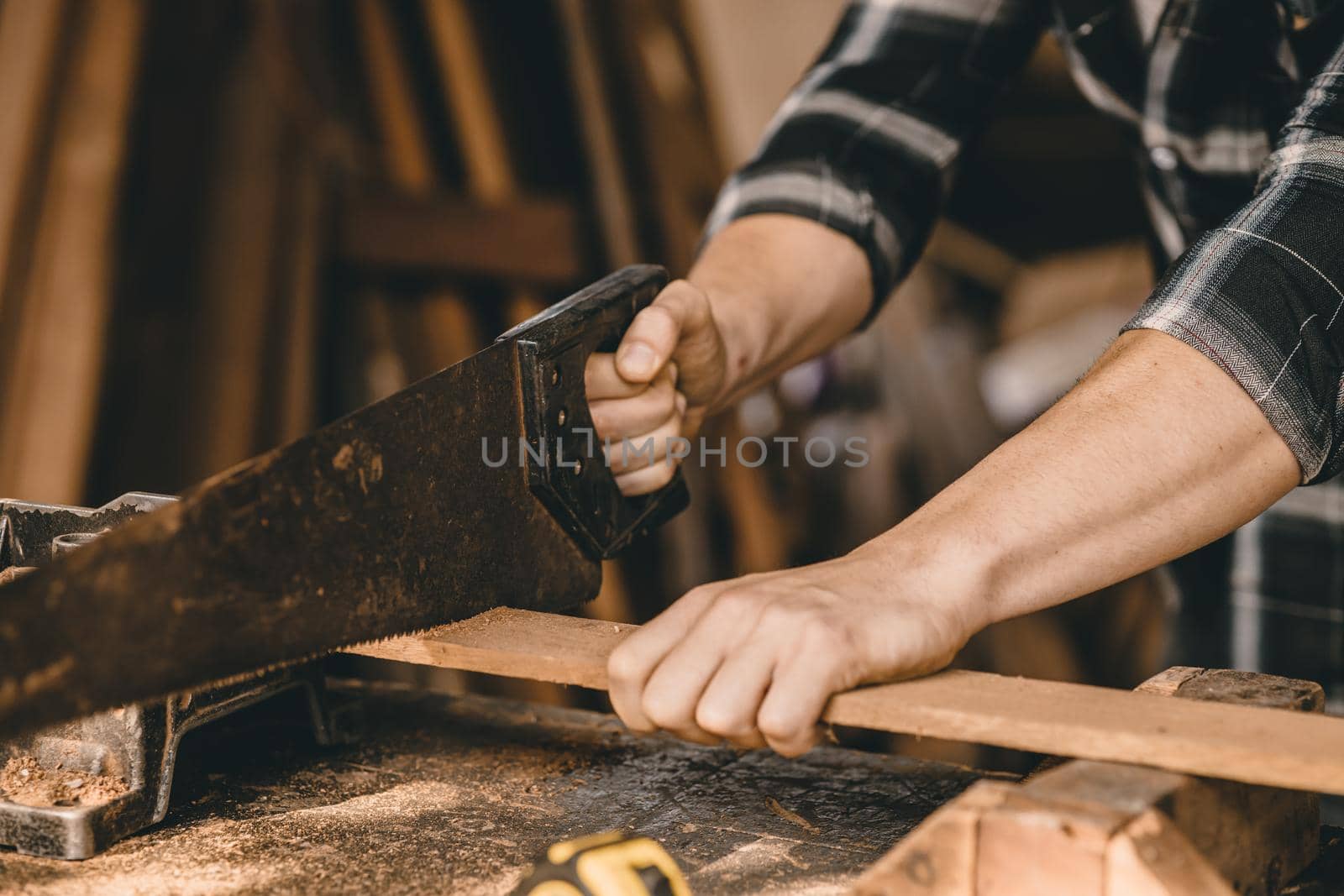 Closeup male builder worker hand using wood saw to sawing wood in furniture workshop. by qualitystocks